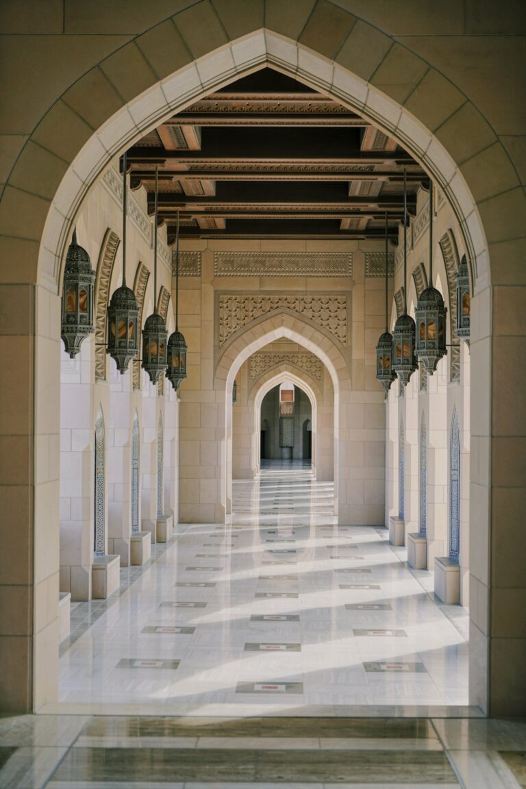 Couloir d’arches d’une mosquée éclairé par des lanternes